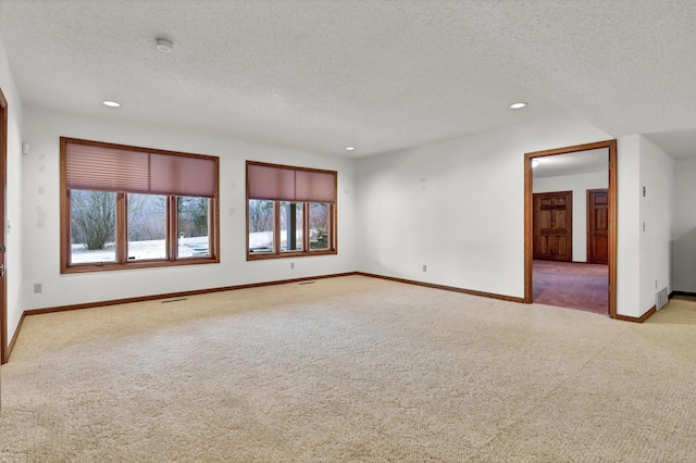 unfurnished room featuring light colored carpet and a textured ceiling