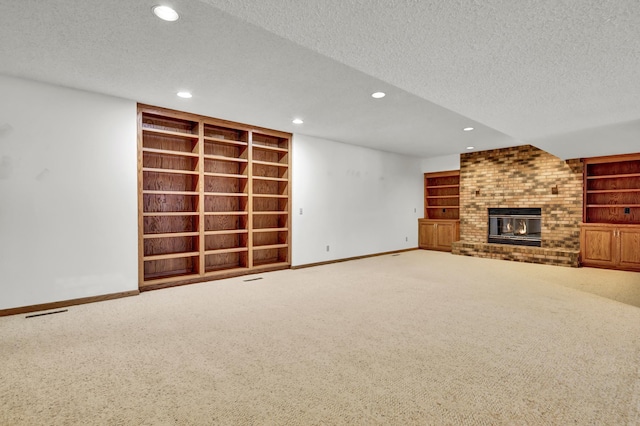 unfurnished living room featuring built in shelves, a brick fireplace, and a textured ceiling