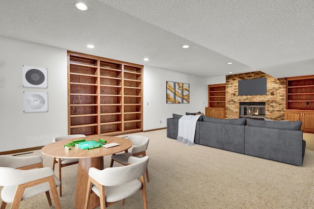 dining room featuring a brick fireplace, light carpet, a textured ceiling, and built in shelves