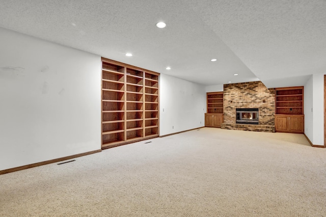 unfurnished living room featuring built in shelves, a fireplace, light carpet, and a textured ceiling