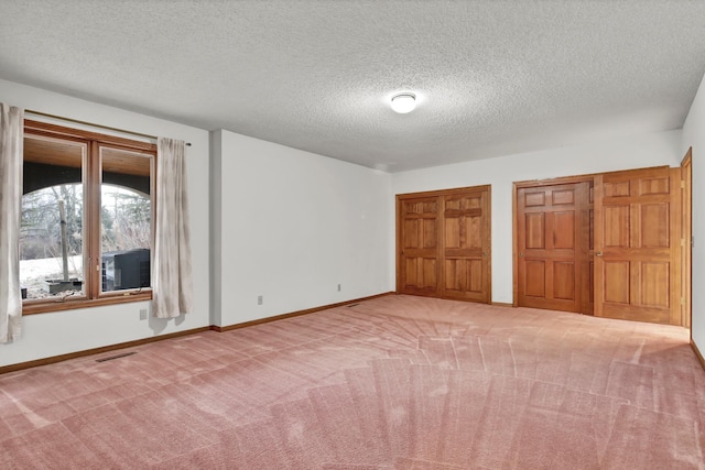 unfurnished bedroom featuring multiple closets, carpet floors, and a textured ceiling