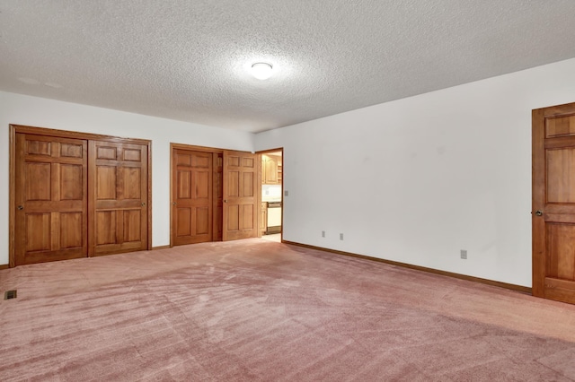 unfurnished bedroom with multiple closets, carpet floors, and a textured ceiling