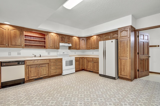 kitchen with white appliances, a raised ceiling, sink, and a textured ceiling