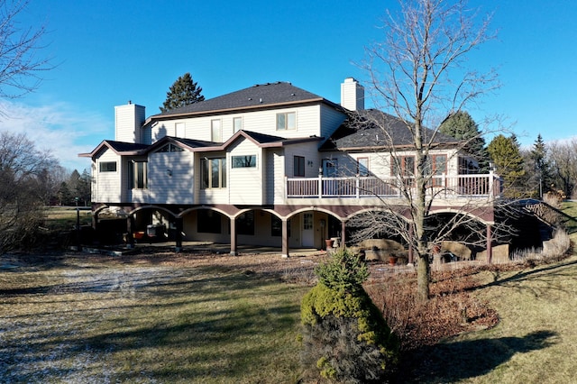 back of property featuring a lawn, a chimney, and a deck