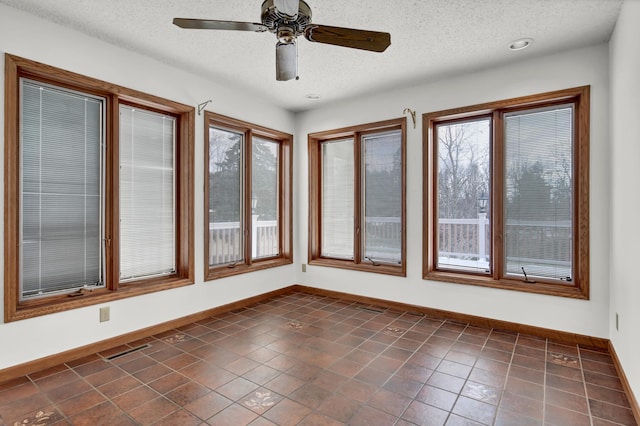 unfurnished sunroom with visible vents, a healthy amount of sunlight, and a ceiling fan