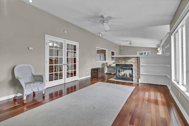 living room with wood finished floors, baseboards, lofted ceiling, a fireplace, and french doors