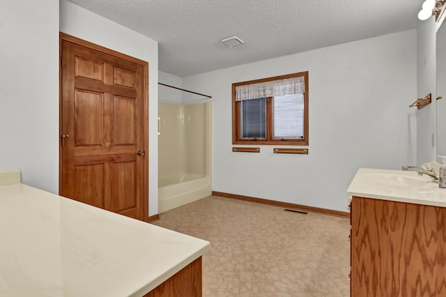 full bath featuring baseboards, washtub / shower combination, vanity, tile patterned floors, and a textured ceiling