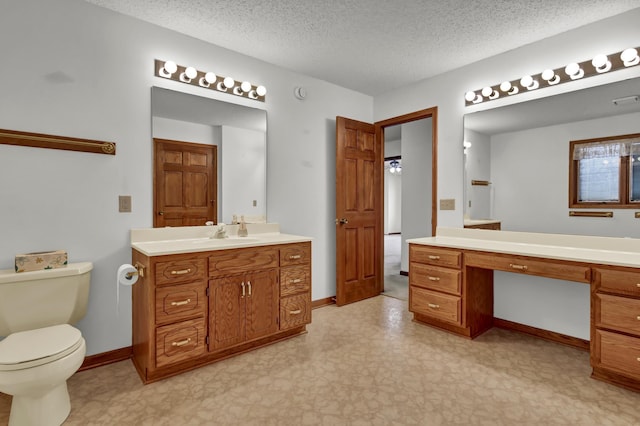 bathroom with vanity, baseboards, a textured ceiling, tile patterned floors, and toilet