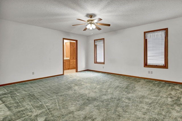 carpeted spare room featuring ceiling fan, a textured ceiling, and baseboards