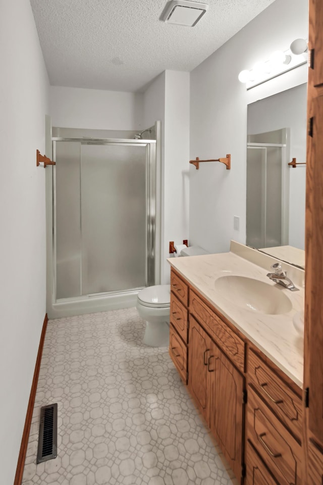 full bath with visible vents, a shower stall, toilet, vanity, and a textured ceiling