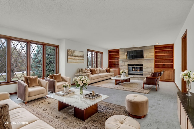 living room featuring built in shelves, baseboards, light carpet, a fireplace, and a textured ceiling