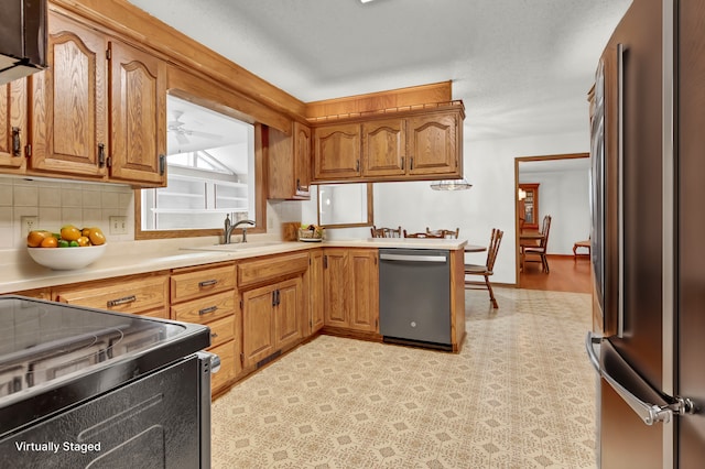 kitchen with a sink, stainless steel appliances, brown cabinetry, and light countertops