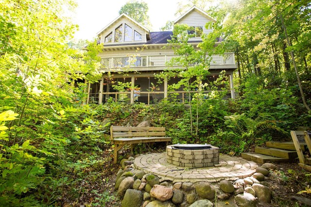 back of house with a fire pit and a sunroom