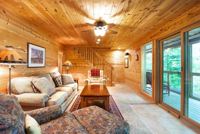 living room with wooden walls, wooden ceiling, stairway, and ceiling fan