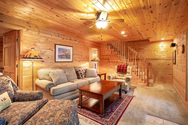 living room featuring stairway, wooden walls, wooden ceiling, carpet flooring, and ceiling fan