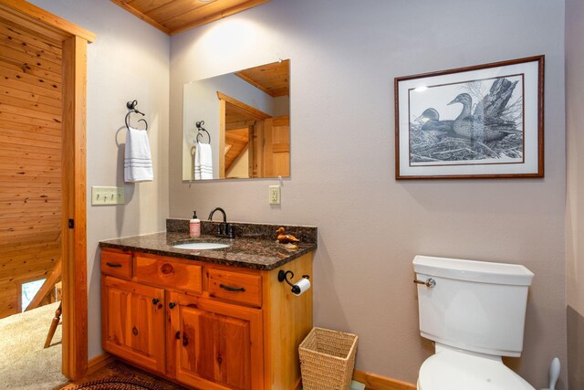 half bathroom with vanity, wooden ceiling, and toilet