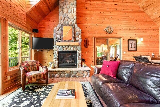 living room featuring wooden walls, wood ceiling, a fireplace, wood finished floors, and high vaulted ceiling