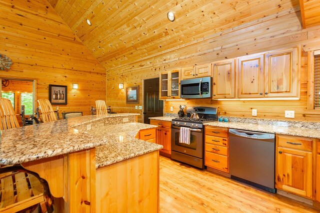 kitchen featuring a kitchen bar, light wood-style flooring, appliances with stainless steel finishes, wood walls, and wooden ceiling