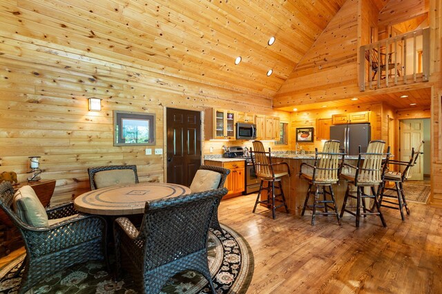 dining area with high vaulted ceiling, light wood-style flooring, and wooden ceiling