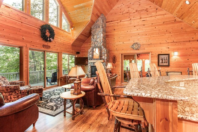 living room with wood ceiling, light wood finished floors, a fireplace, and wood walls