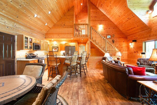 living room with stairway, wood ceiling, light wood-style floors, and high vaulted ceiling