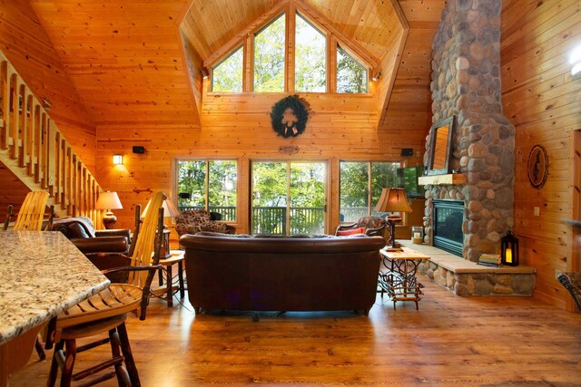 living room with wooden walls, a healthy amount of sunlight, a fireplace, and wood finished floors