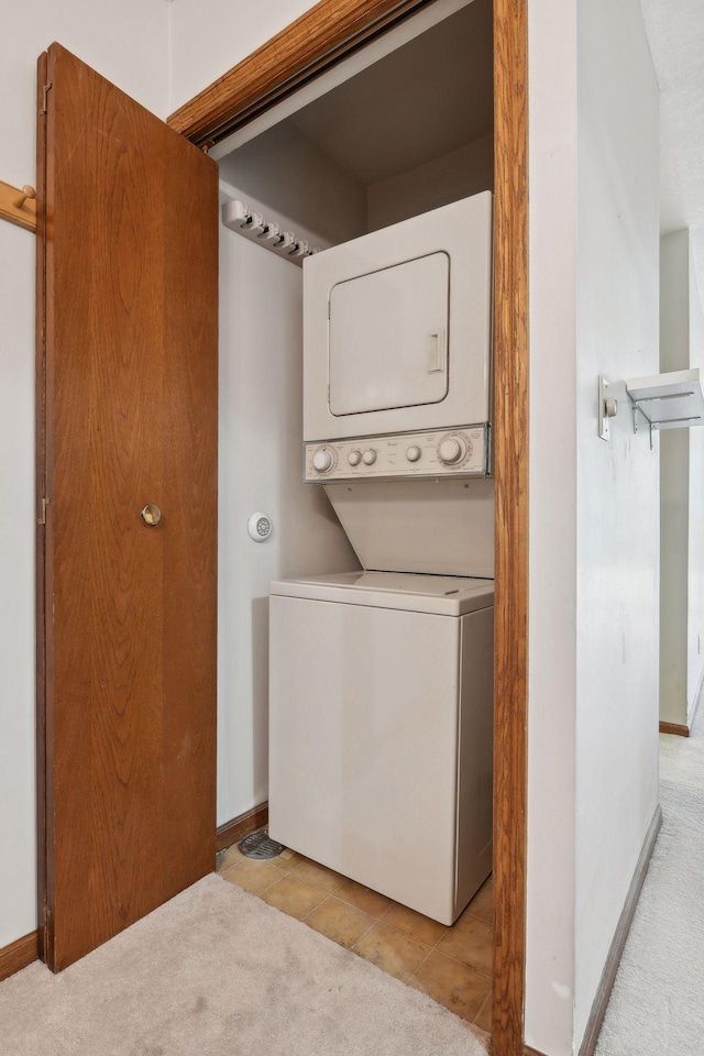 washroom featuring light tile patterned floors and stacked washer and dryer