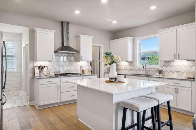 kitchen with sink, wall chimney exhaust hood, and white cabinets