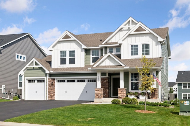 craftsman-style house featuring stone siding, a front yard, board and batten siding, and driveway