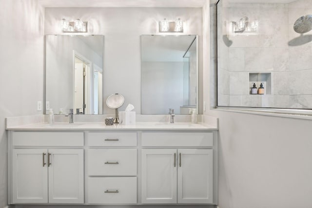 bathroom with double vanity, tiled shower, and a sink