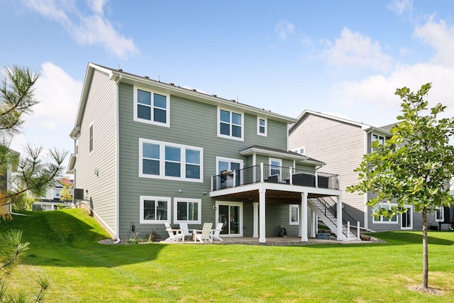 rear view of house featuring a wooden deck, a lawn, stairs, and a patio area