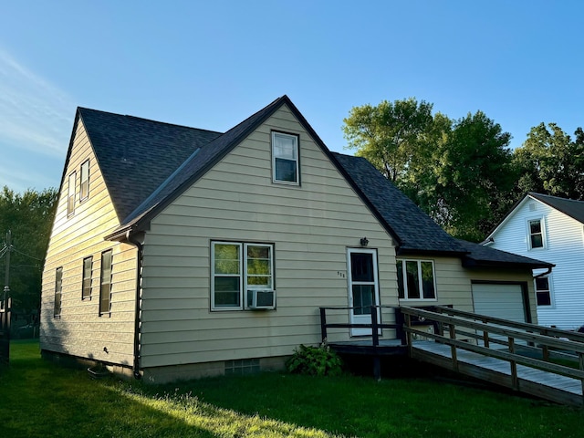 rear view of property featuring a lawn, a deck, and a garage