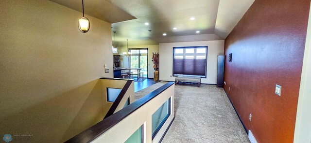 hall featuring lofted ceiling, a chandelier, and carpet flooring