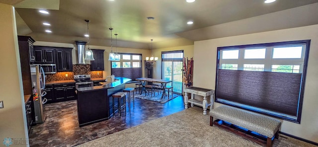 kitchen featuring a chandelier, a kitchen island with sink, a kitchen bar, hanging light fixtures, and stainless steel appliances