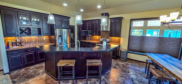 kitchen featuring decorative backsplash, a kitchen breakfast bar, appliances with stainless steel finishes, and a kitchen island with sink