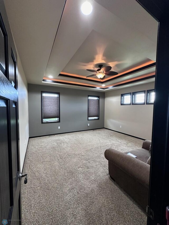 interior space with a raised ceiling and ceiling fan