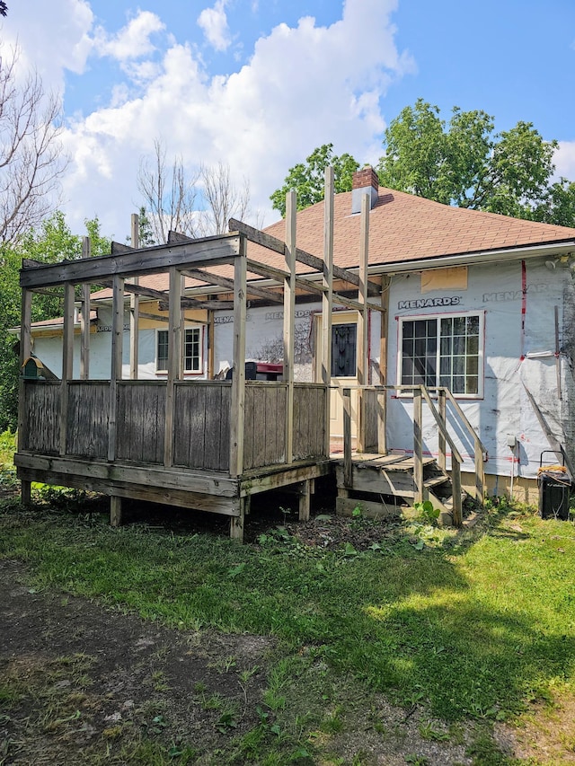 back of property featuring a lawn, a pergola, and a wooden deck