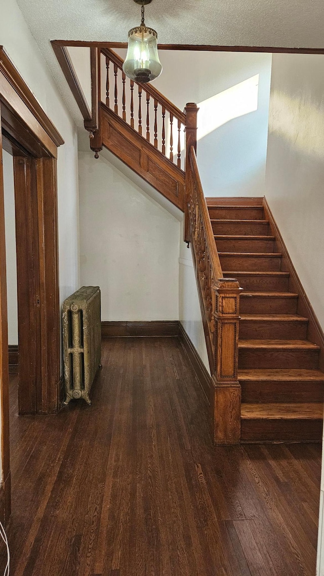 stairway featuring a textured ceiling, crown molding, hardwood / wood-style floors, and radiator heating unit