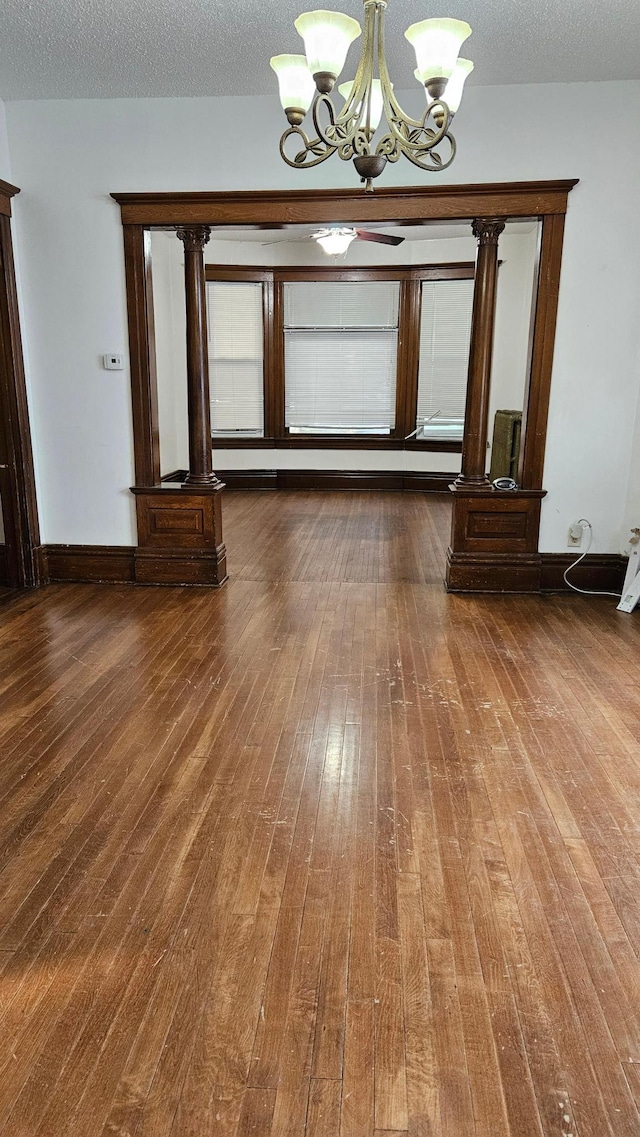 unfurnished dining area featuring a notable chandelier, a textured ceiling, and dark hardwood / wood-style flooring