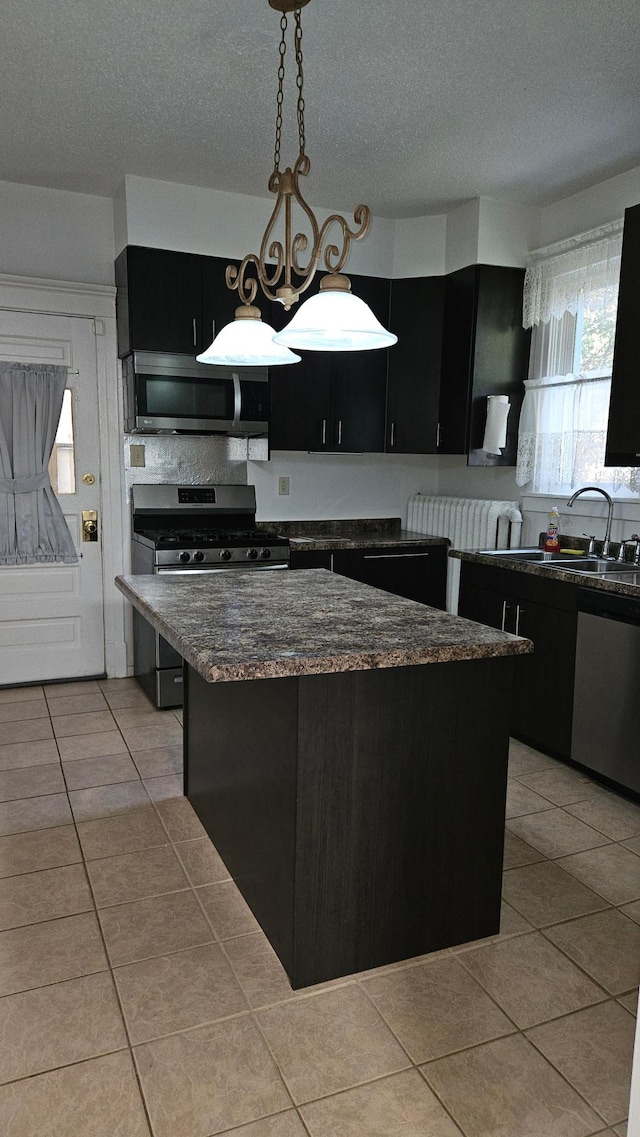 kitchen with hanging light fixtures, sink, a kitchen island, a textured ceiling, and stainless steel appliances