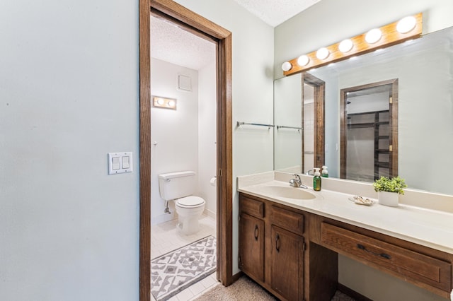 bathroom featuring vanity, tile patterned flooring, toilet, and a textured ceiling