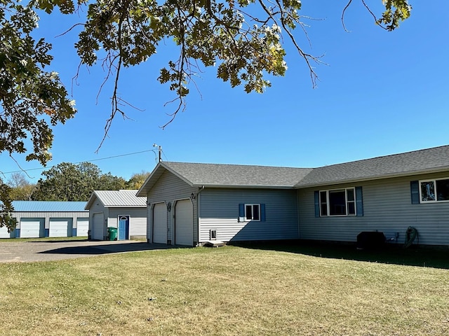 back of house featuring a lawn and a garage