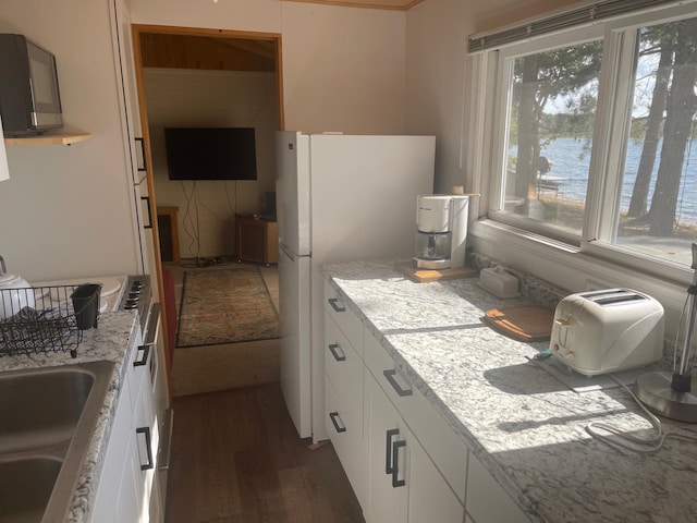 kitchen with light stone counters, white cabinets, sink, dark wood-type flooring, and white fridge