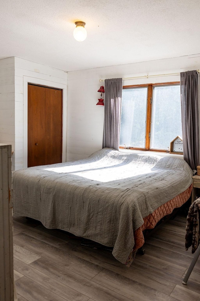 50165 Sailer Rd, Frazee, MN 56544 - bedroom with a textured ceiling, a closet, dark hardwood / wood-style floors, and wooden walls
