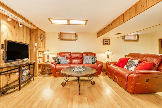 living room featuring wooden walls, light hardwood / wood-style floors, and beamed ceiling