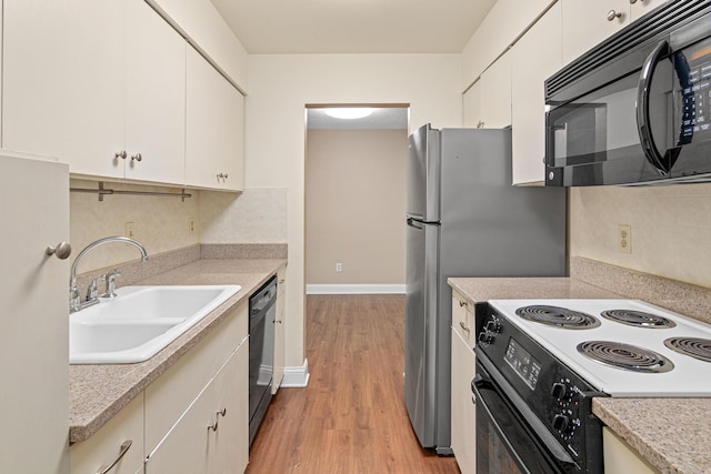 kitchen with black appliances, sink, white cabinetry, decorative backsplash, and light hardwood / wood-style flooring