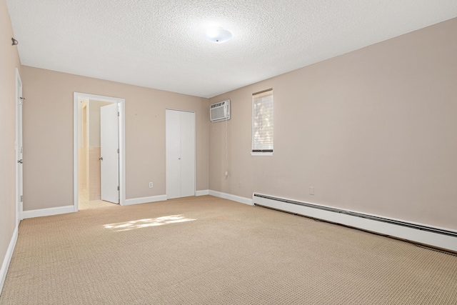 unfurnished bedroom with a baseboard heating unit, a wall unit AC, a textured ceiling, and light colored carpet