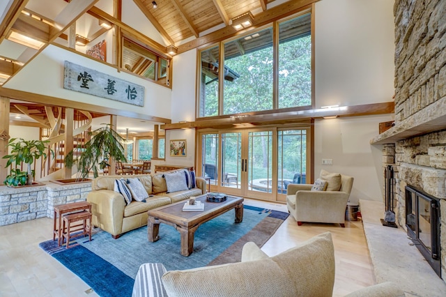 living room with high vaulted ceiling, wooden ceiling, plenty of natural light, and a stone fireplace