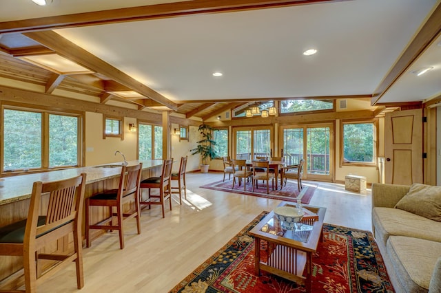 living room featuring light wood-type flooring, plenty of natural light, and lofted ceiling with beams