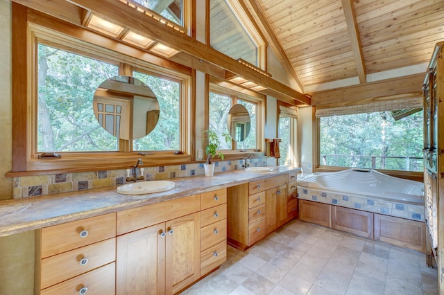 bathroom featuring vaulted ceiling with beams, vanity, a bathing tub, and a healthy amount of sunlight